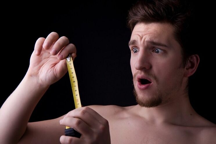Ein Mann maß mit einem Maßband seinen Penis vor einer Vergrößerungsoperation